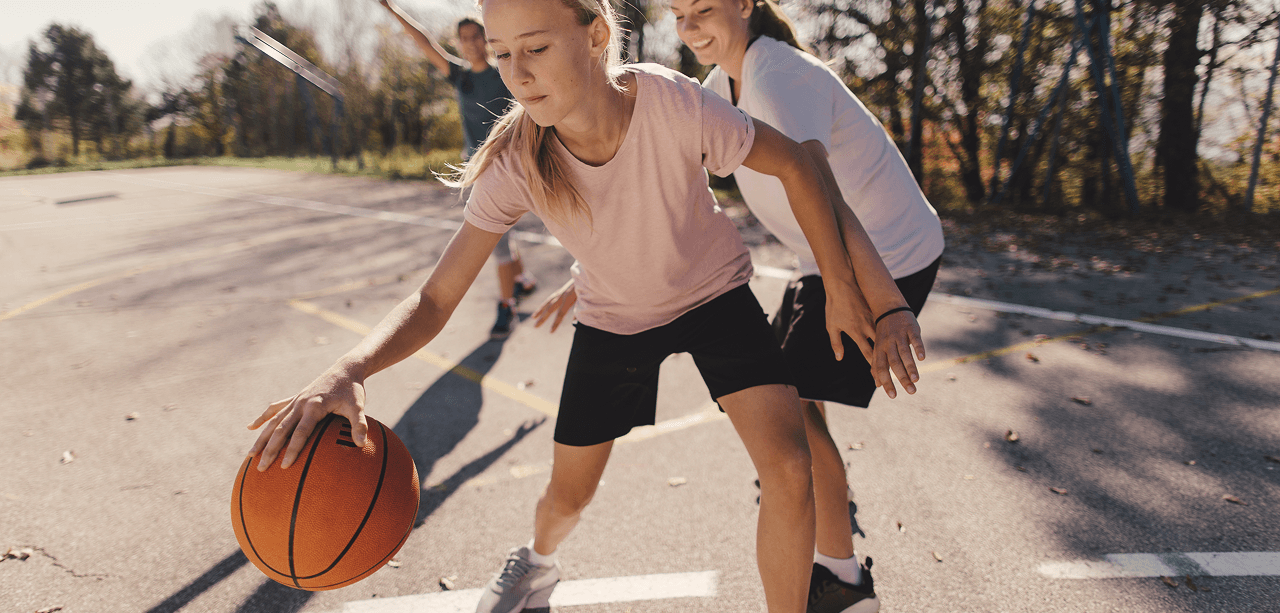 Barn spelar basket med hjälp av Piffl och en tjej studsar basketbollen.